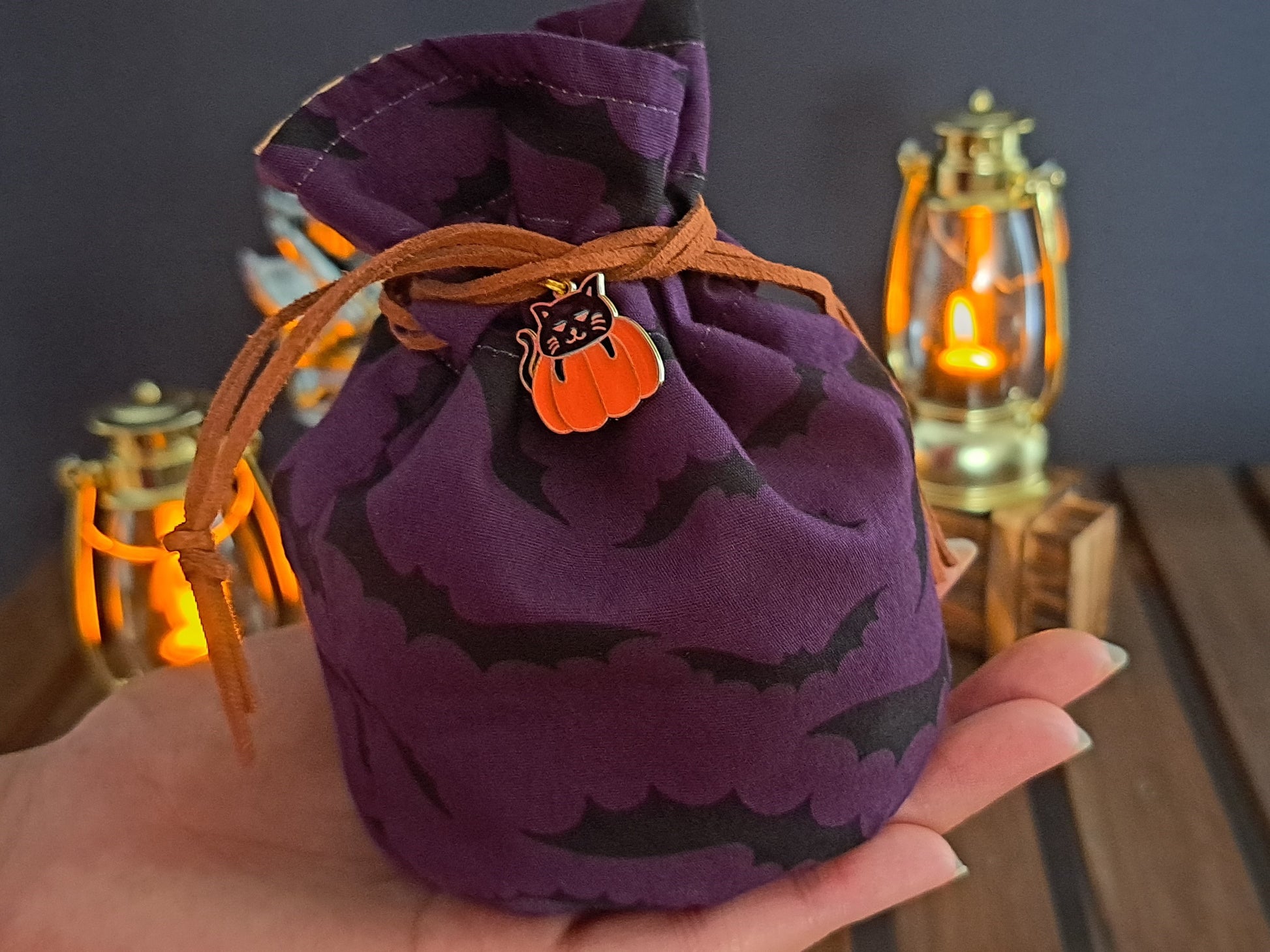 Zoomed in Handmade Dice bag made of purple fabric with black bats on it with a pumpkin charm